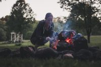 Stoking the campfire with the ceremonial altar in the background.